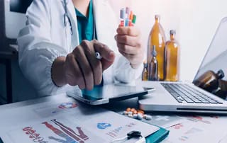 Pharma professional reviewing GMP compliance data and lab samples for a quality audit.